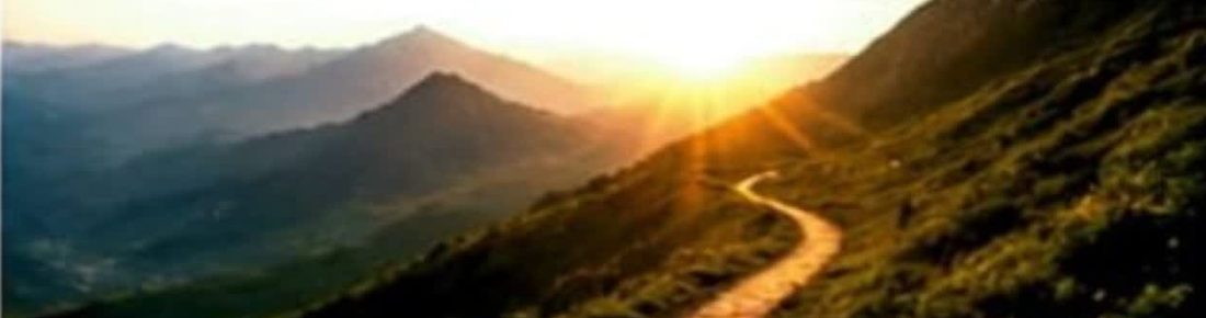 A winding mountain path leading towards a bright sunrise